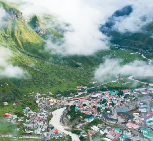 drone view of Munsyari showing hills, river and buildings on bank of river